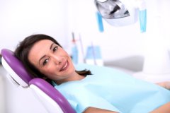 Smiling brunette lady in dental chair awaiting a root canal
