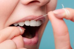 Close up of a woman demonstrating the correct flossing technique