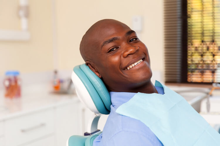 Smiling black man in dental chair for a restorative treatment