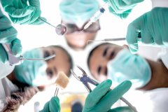 Masked dental staff looking down on patient ready for oral surgery