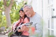 Grandpa and young granddaughter playing the guitar.