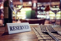 Table in a restaurant with a reserved sign and wine glass.